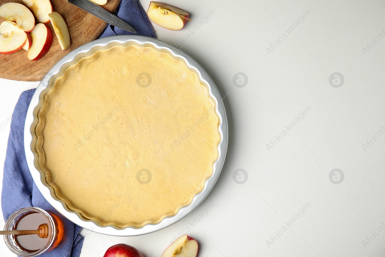 Photo of Raw traditional English apple pie and ingredients on white table, flat lay. Space for text