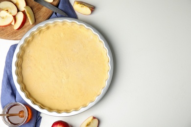 Photo of Raw traditional English apple pie and ingredients on white table, flat lay. Space for text