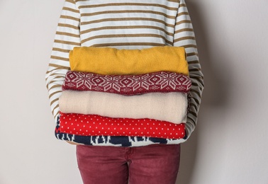 Photo of Woman holding stack of winter clothes on white background