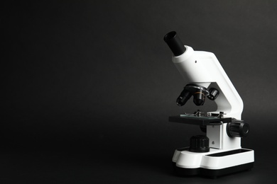 Photo of Modern microscope on black background, space for text. Medical equipment