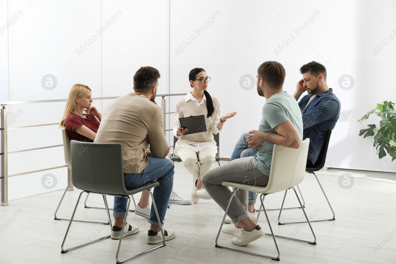 Photo of Psychotherapist working with group of drug addicted people at therapy session indoors