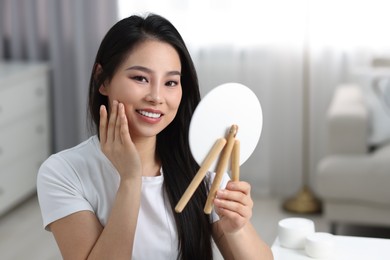 Woman with perfect skin looking at mirror indoors