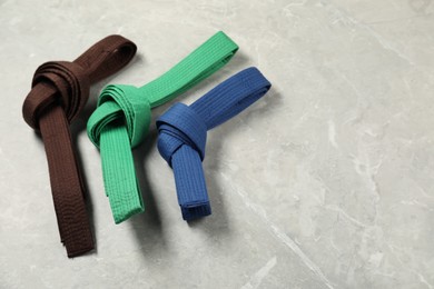 Photo of Colorful karate belts on gray marble background, flat lay. Space for text