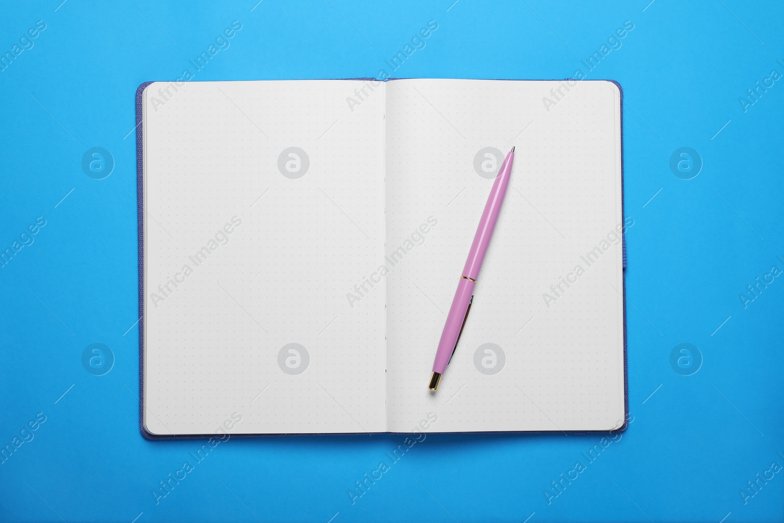 Photo of Open notebook and pen on light blue background, top view