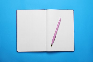 Open notebook and pen on light blue background, top view