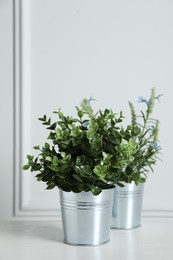 Photo of Aromatic potted herbs on wooden table near white wall