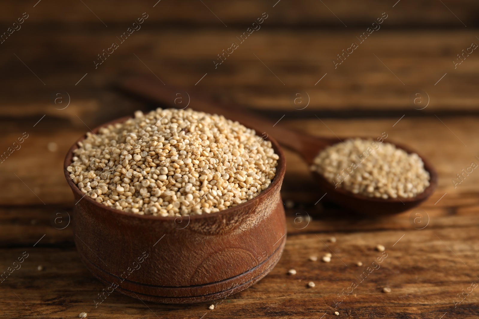 Photo of Bowl with white quinoa on wooden table. Space for text