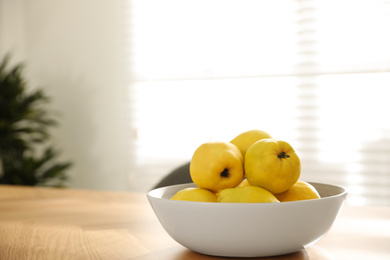 Ripe quinces on wooden table at home