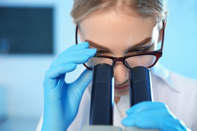 Female scientist using modern microscope in chemistry laboratory