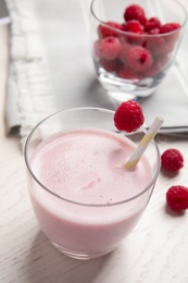 Photo of Tasty fresh milk shake with raspberry on white table, closeup