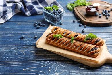 Photo of Fresh delicious puff pastry with sweet berries served on blue wooden table