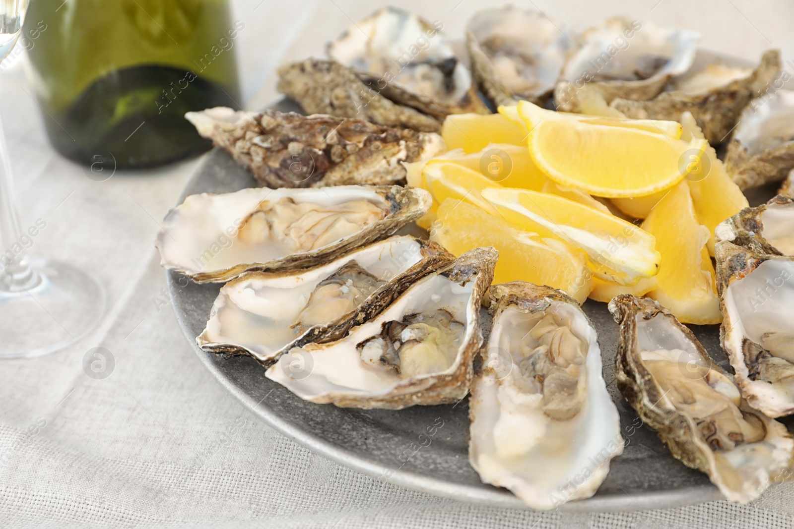 Photo of Fresh oysters with cut juicy lemon on plate, closeup