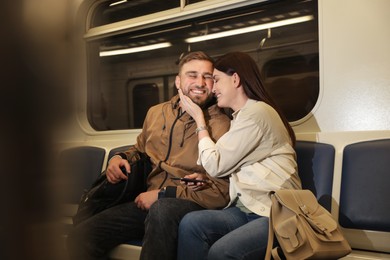 Photo of Happy couple using mobile phone in subway train. Public transport