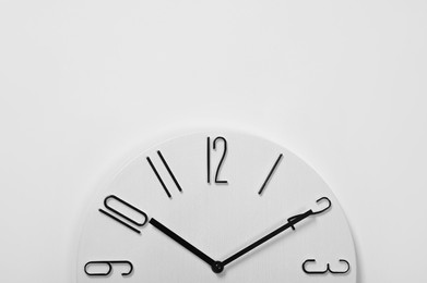 Photo of Stylish analog clock hanging on white wall, space for text