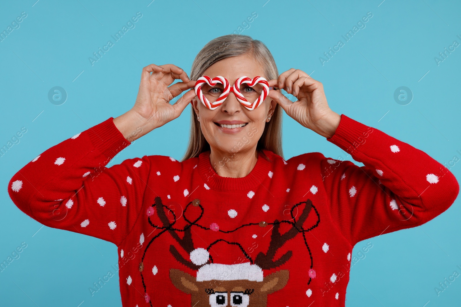 Photo of Senior woman in Christmas sweater and funny glasses on light blue background