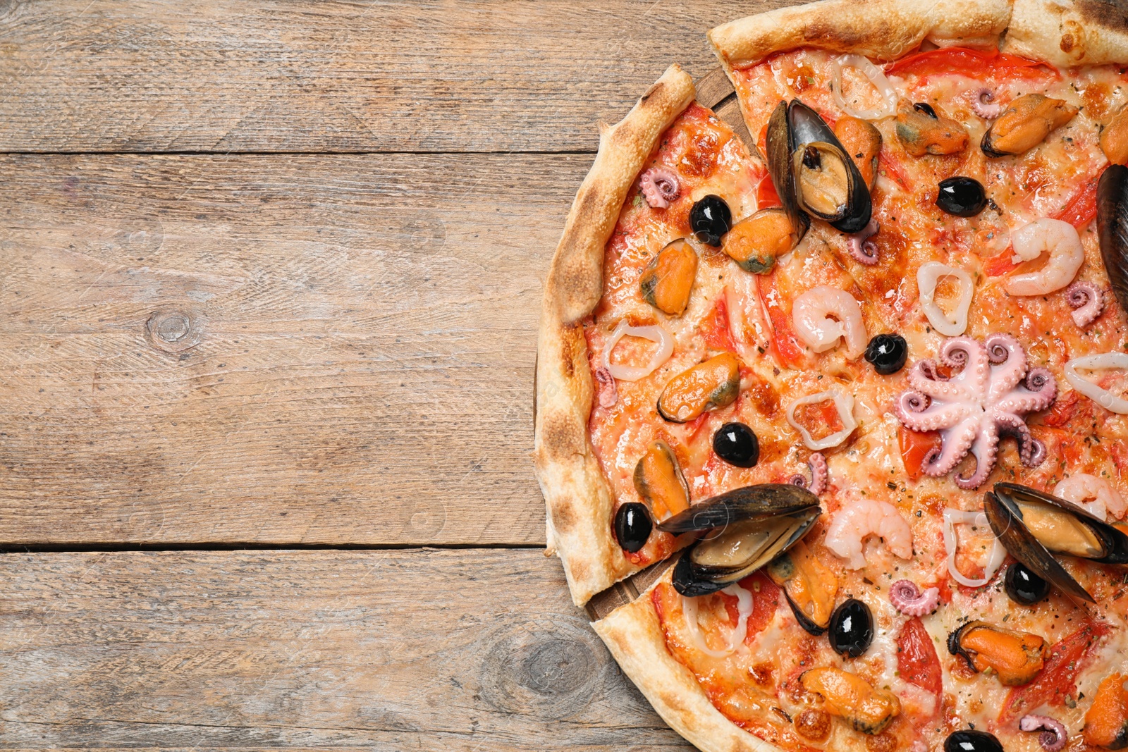 Photo of Tasty pizza with seafood on wooden table, top view. Space for text