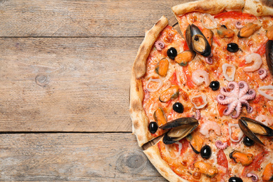 Photo of Tasty pizza with seafood on wooden table, top view. Space for text