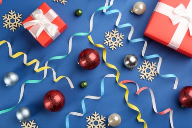 Flat lay composition with serpentine streamers and Christmas decor on blue background