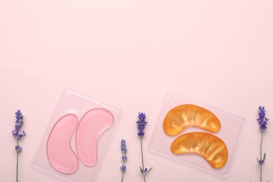 Photo of Packages with different under eye patches and lavender flowers on light pink background, flat lay. Space for text