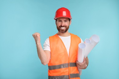 Photo of Architect in hard hat with drafts on light blue background