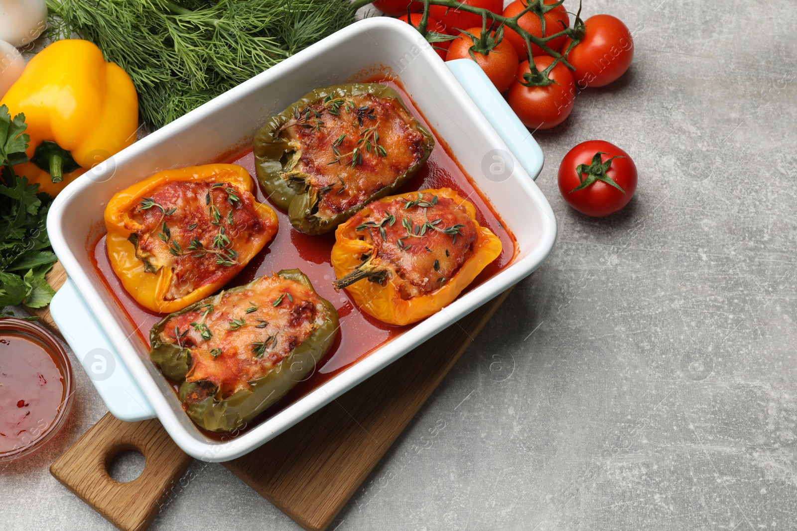 Photo of Tasty stuffed peppers in dish and ingredients on grey table, above view. Space for text