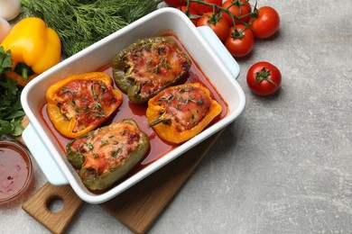 Photo of Tasty stuffed peppers in dish and ingredients on grey table, above view. Space for text