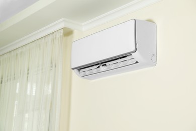 Modern air conditioner on white wall indoors