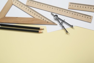 Photo of Different rulers, pencils and compass on yellow background, flat lay. Space for text