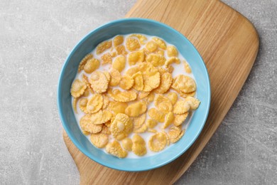 Photo of Tasty cornflakes with milk in bowl on light grey table, top view