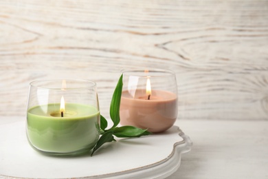 Photo of Board with burning candles and bamboo leaves on light table, space for text