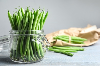 Photo of Fresh green beans in glass jar on grey wooden table, closeup. Space for text