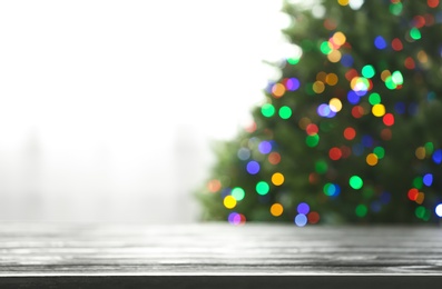 Photo of Empty table and blurred fir tree with colorful Christmas lights on background, bokeh effect. Space for design