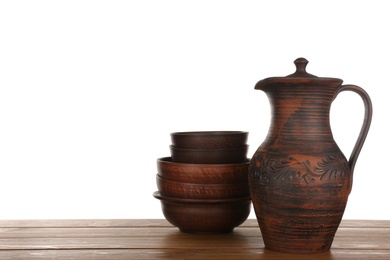 Different clay dishware on wooden table against white background