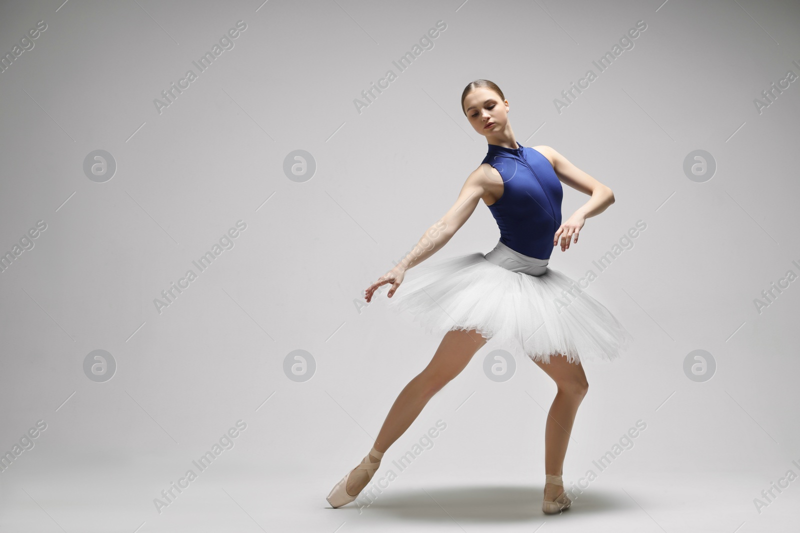 Photo of Young ballerina practicing dance moves on light grey background. Space for text