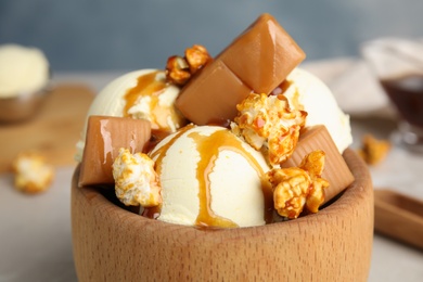 Delicious ice cream with caramel, popcorn and sauce served on table, closeup