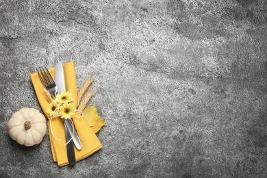 Photo of Cutlery, spikelets, flowers and pumpkin on grey table, flat lay with space for text. Thanksgiving Day celebration