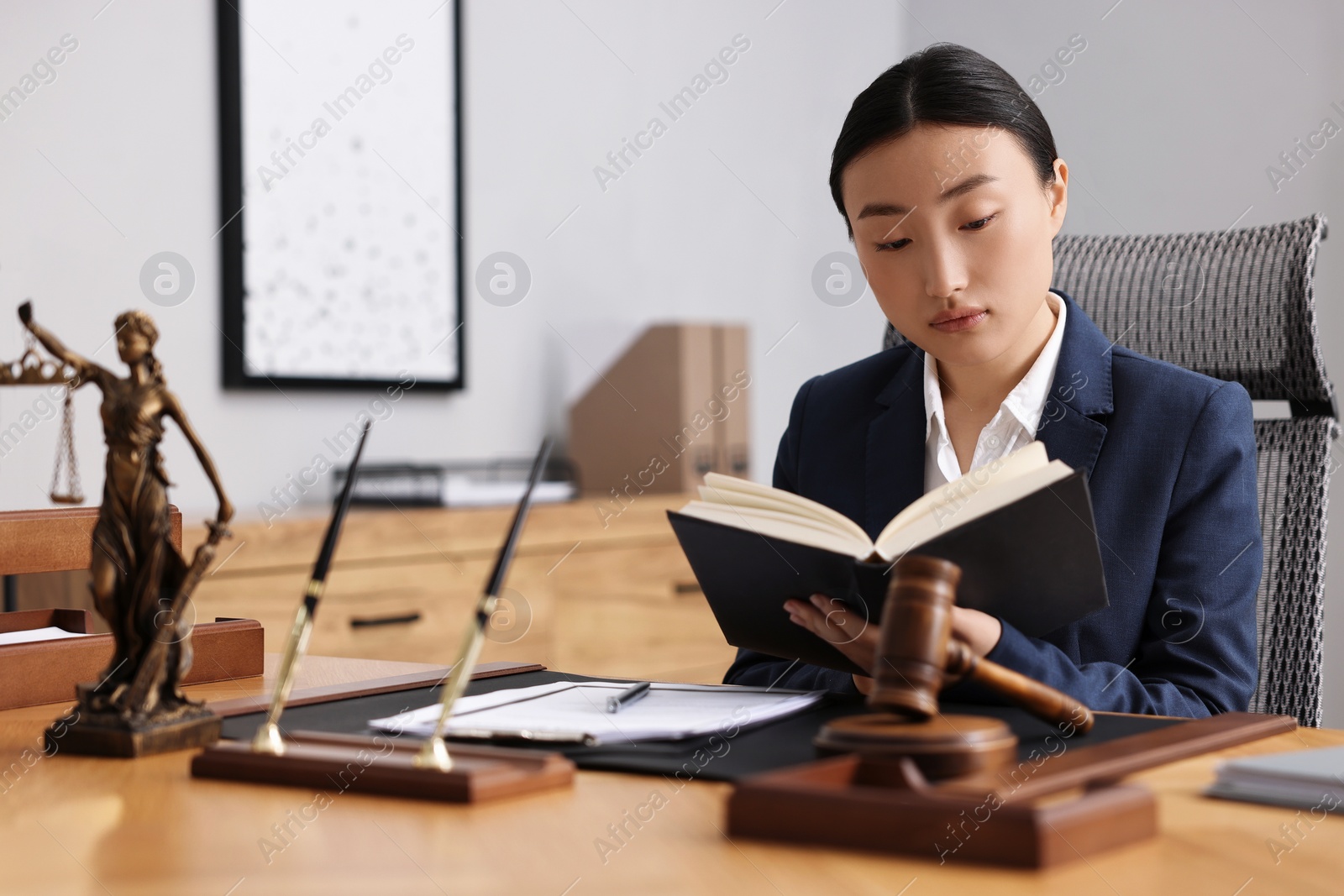 Photo of Notary reading book at table in office