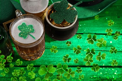 Image of St. Patrick's day. Beer, leprechaun pot of gold and decorative clover leaves on green wooden table, above view. Space for text