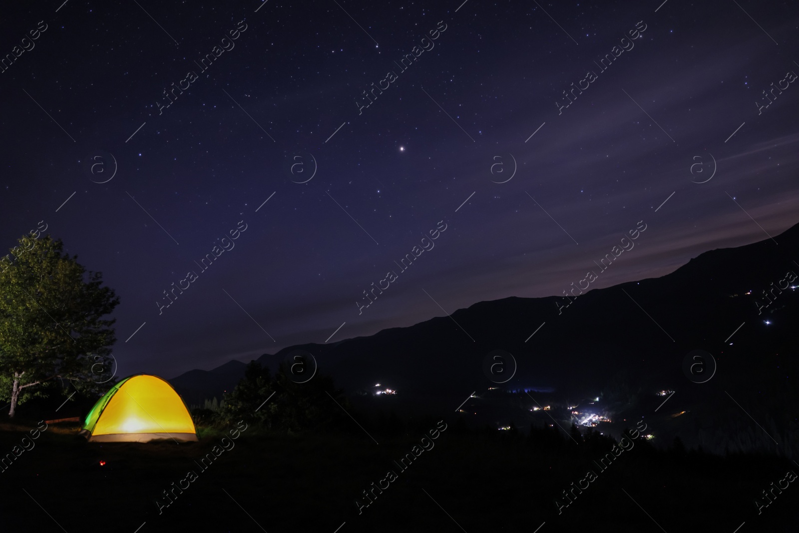 Photo of Beautiful view of mountain landscape with glowing yellow camping tent at night