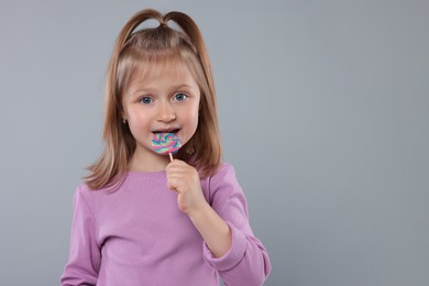 Photo of Portrait of cute girl with lollipop on light grey background. Space for text