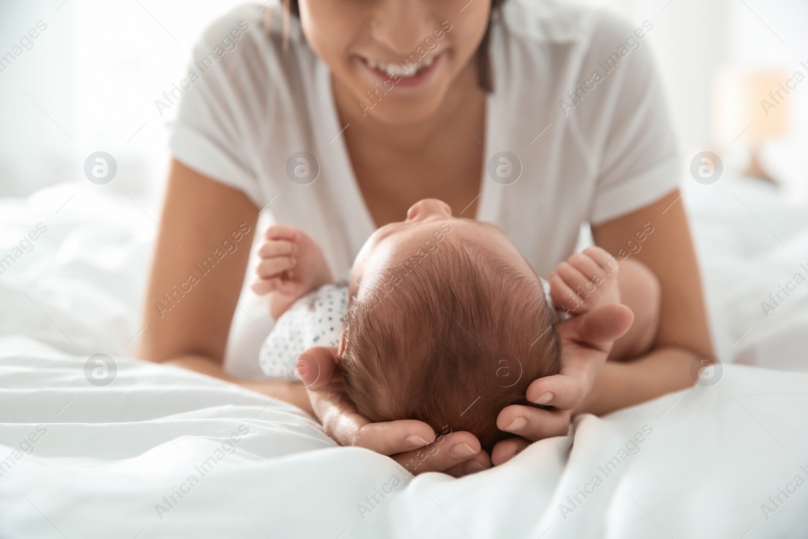 Photo of Young woman with her newborn baby on bed, closeup