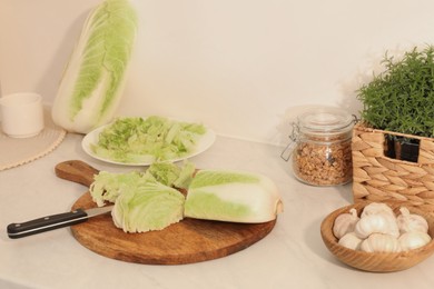 Photo of Cut fresh chinese cabbage and knife at white kitchen table