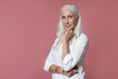 Photo of Portrait of beautiful mature woman on pink background, space for text