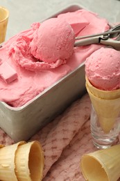 Delicious ice cream in container and wafer cones on table