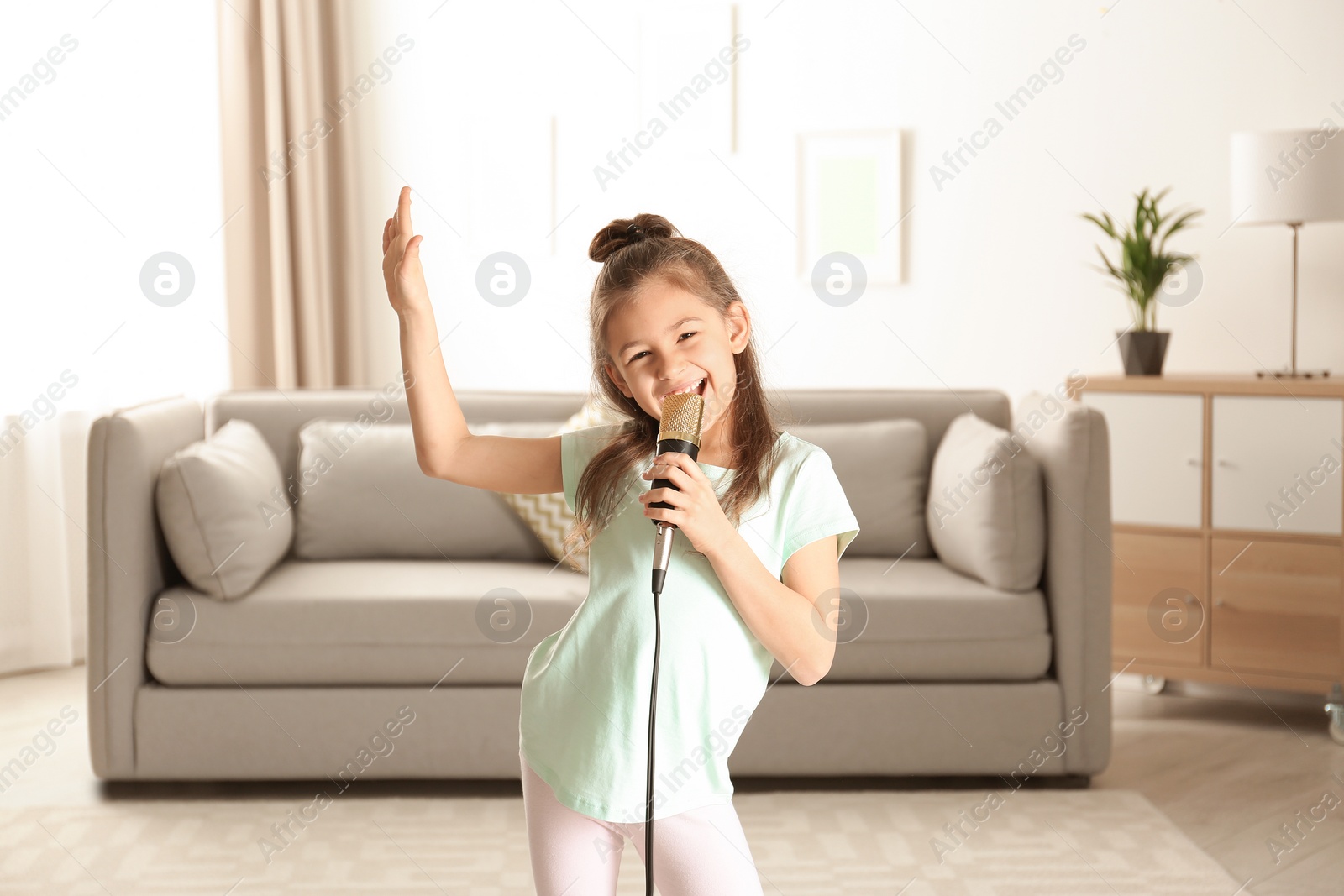 Photo of Cute funny girl with microphone in living room