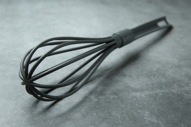 Plastic whisk on gray table, closeup. Kitchen tool