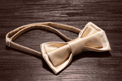 Photo of Stylish beige bow tie on wooden table, closeup