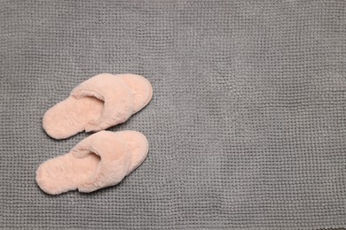 Photo of Slippers on soft grey bath mat, flat lay. Space for text