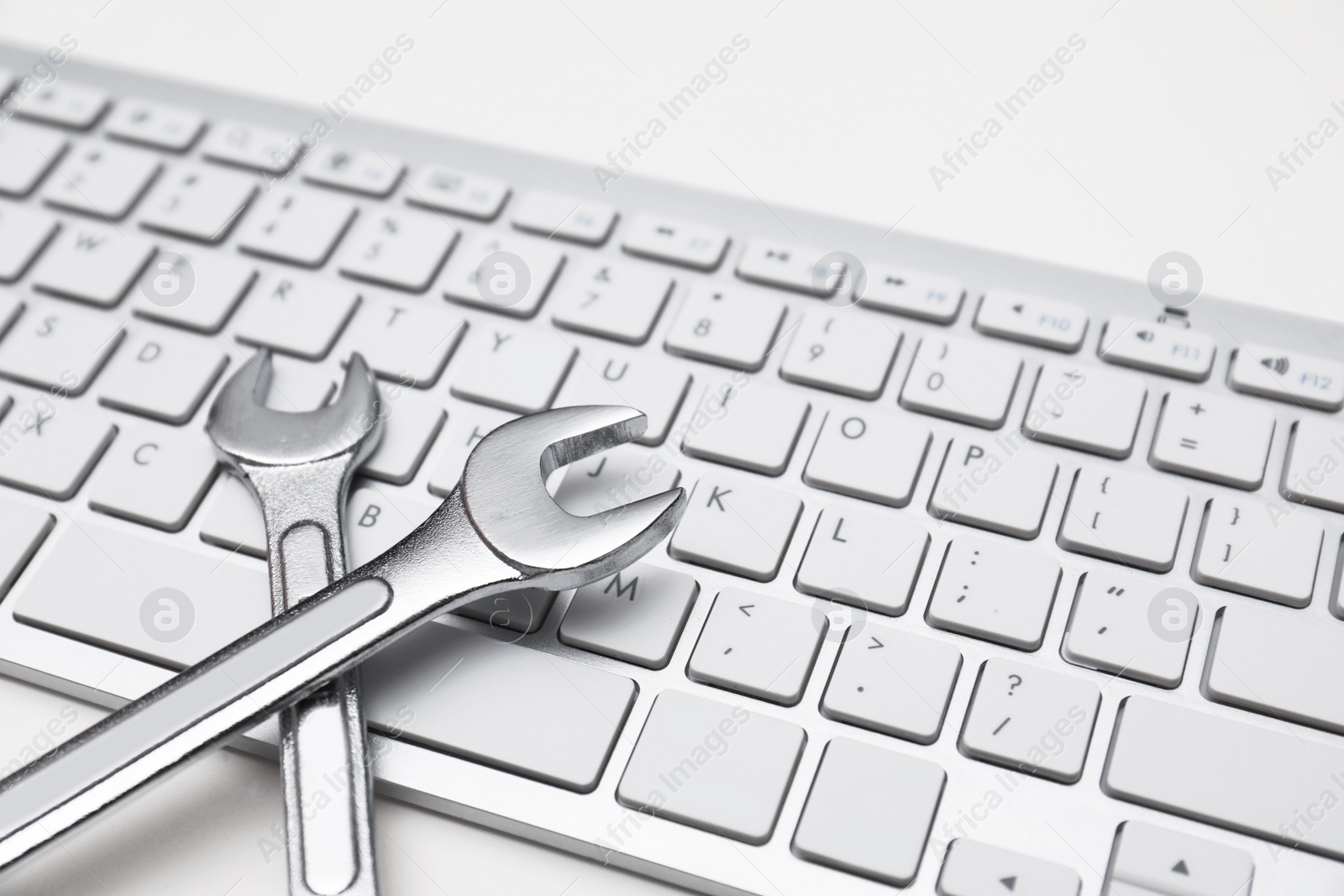 Photo of Wrenches and computer keyboard on light background. Concept of technical support