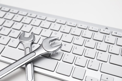 Photo of Wrenches and computer keyboard on light background. Concept of technical support